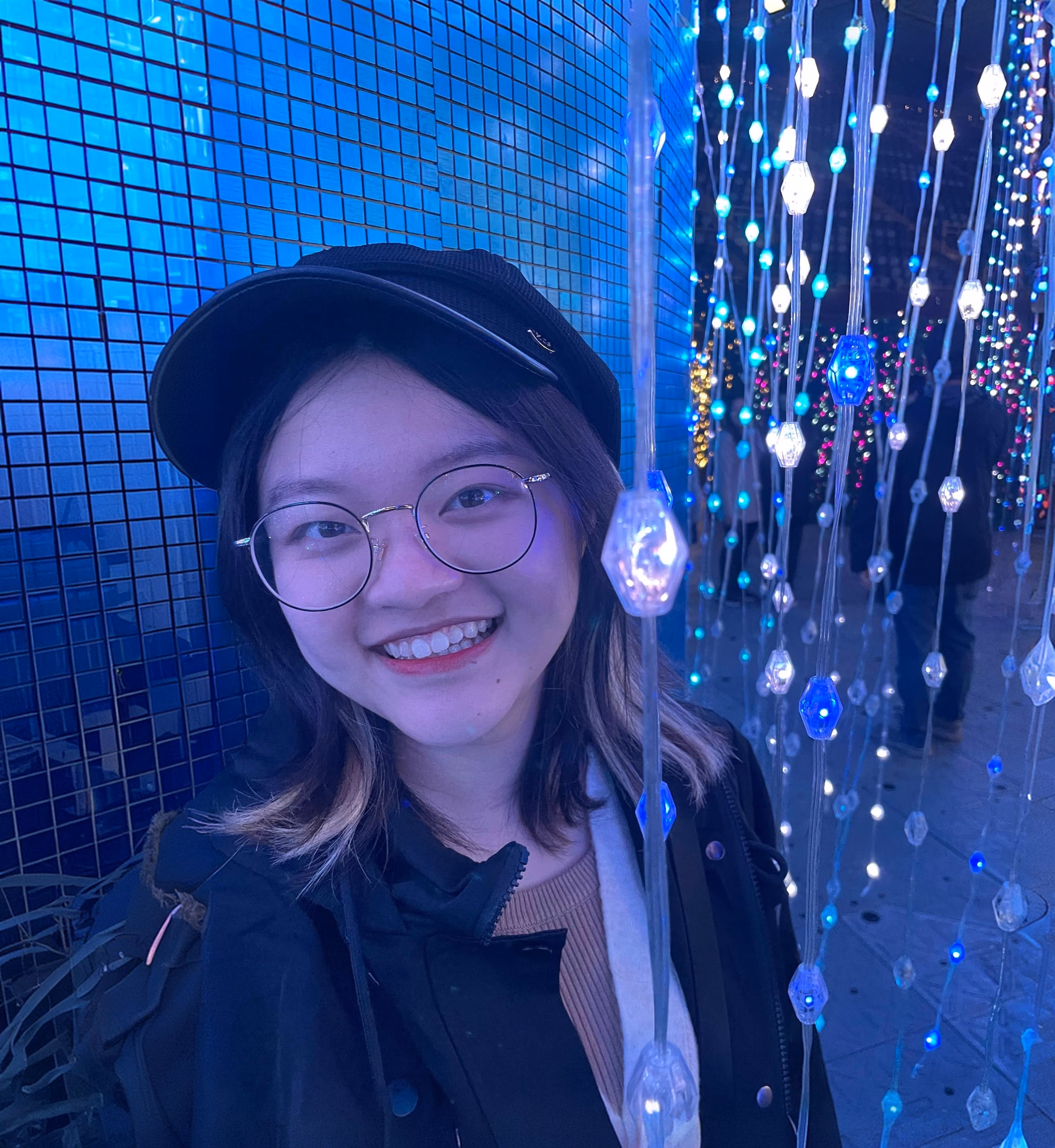 Christy Yu, smiling in a black cap and round glasses